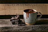 Ceramic cup of hot spicy homemade chocolate winter drink with chopped dark chocolate bar