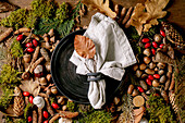 Empty black ceramic plate with cloth napkin over ambiance magic autumnal forest background