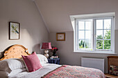 Bedroom with wooden bed, patterned bedspread and view of trees out the window