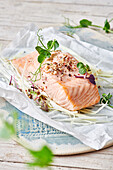 Delicious fish fillet with green pea sprouts and seasonings on baking paper