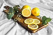 Colorful whole lemons near wavy plant sprig on wooden chopping board