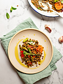 Lentil salad with vegetables and herbs served in plate on marble table
