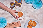 Crop anonymous person with traditional Chinese mooncake on plate placed on table with herb tea and baking mold