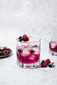 Glass of refreshing cocktail with blackberry and raspberry on wooden toothpick