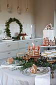 Weihnachtlich gedeckter Tisch mit Lebkuchenhäusern und Zweigen