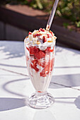 An ice cream sundae with red fruits and cream