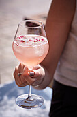 Hand holding stemmed glass with summer berry drink