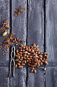 Hazelnuts with and without shell as well as nutcracker on wooden background