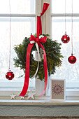 Christmas window decoration with wreath and red baubles