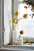 Golden dried flowers in white ceramic vases on a windowsill