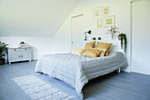 Bright bedroom with double bed, decorative throw pillows and plants