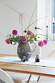 Flower arrangement with pompom dahlias in grey vase on dining table