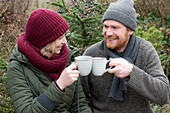 Man and woman toasting with mulled wine in ceramic mugs