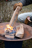 Man puts log in the fire bowl