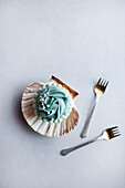 Monoportion cupcake with blue frosting in a clam shell