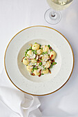 Gnocci with grated truffle, Parmesan cheese, peas and bacon served with a glass of white wine