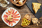Spanische Tapas: Schinken, Oliven und Tortilla mit Mandeln und Brot auf Holztisch