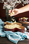 Colomba di Pasqua - traditional italian easter cake with almonds, woman sprinkling almonds