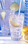 Two glasses of sparkling mineral water, straw, ice cubes, lemon, and lime