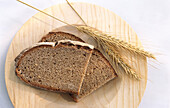 Two slices of rye bread and two ears of rye on a wooden plate