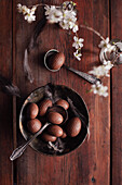 Vintage bowl with chocolate eggs and feathers