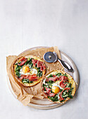 Mini pizzas with spinach, ham, and fried egg