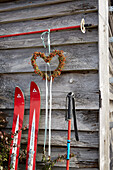 Decorative skis and heart-shaped wreath on a wooden wall outdoors