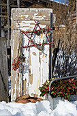 Weathered window shutter in the snow decorated with berries and twigs