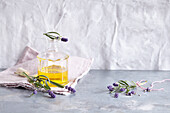 Lavendelöl in einem Fläschchen, daneben Lavendelblüten