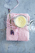 Cremetiegel und Lavendelblüten auf rosa Handtuch