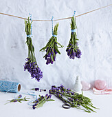 Aufgehängte Lavendelsträußchen, darunter blaues Küchengarn und rosa Herzen aus Rosenquarz