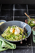 Spaghetti with zucchini strips, kale pesto, parmesan, poached egg and cress micro greens