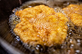Schnitzel fried in oil in a pan