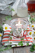 Windlichtglas, dekoriert mit Herz aus Kamillenblüten und roter Schnur