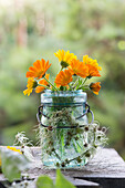 Bouquet of marigolds in a glass with clematis heart