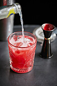 Roter Cocktail in einem Glas mit Eiswürfeln