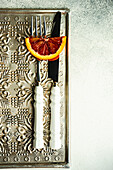 Red sicilian orange slice and vintage cutlery on rustic background