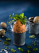 Breakfast egg with a face and herbs in an Easter egg cup