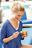 Blonde Frau in blauem Shirt mit Dessert in der Hand
