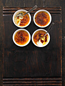 Four bowls of crème brûlée on a wooden base
