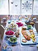 Christmas table laid with baked salmon and various side dishes