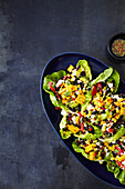 Salat aus geröstetem Mais, schwarzen Bohnen und Feta serviert in Salatblättern