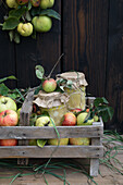 Holzkiste mit Quitten, Äpfeln, Walnüssen und Quittenmus
