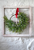 Weihnachtskranz an weißem Fensterrahmen mit rotem Band