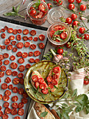 Dried tomatoes on a baking tray, tomato crostini, and pickled tomatoes with herbs