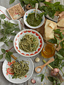 Spaghetti with basil pesto surrounded by ingredients