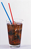 Glass of cola with ice cubes and straws