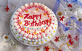 Geburtstagstorte mit brennenden Kerzen und der Aufschrift 'Happy Birthday'