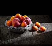 Peaches and apricots in the sunlight on a rustic wooden surface