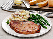 A bone in pork chop with green beans and mashed potatoes